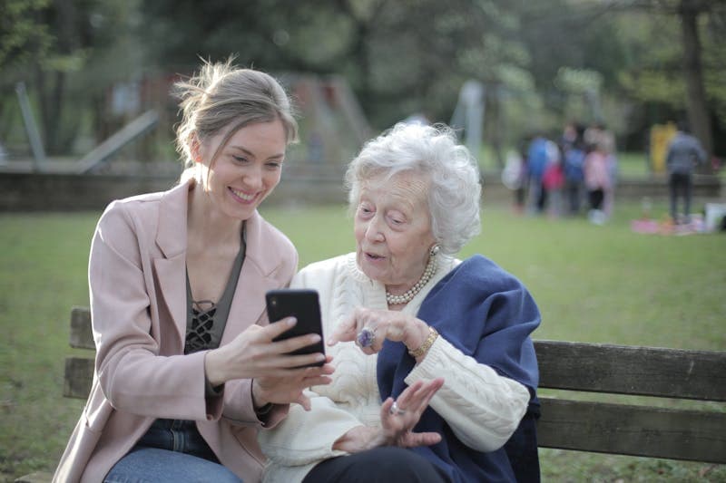 Elderly woman being assisted with smartphone technology