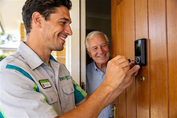 Innogreen technician installing a video doorbell with a senior homeowner